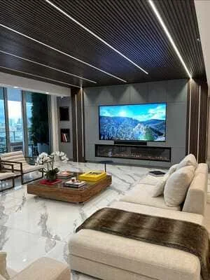 Modern living room with marble floors, metal ceiling, linear lights, and built-in TV wall