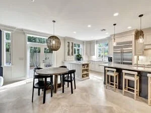 Modern kitchen with white cabinetry, stainless steel appliances, concrete flooring, and black dining table