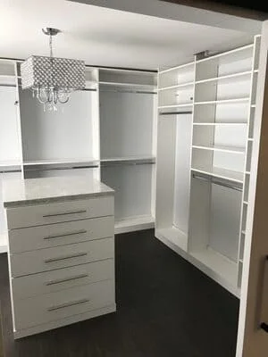 White built-in closet with shelving, drawers, and hanging rod system