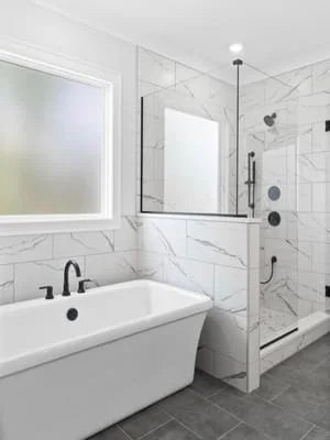 Marble tile bathroom with freestanding tub, frameless shower, and custom vanity