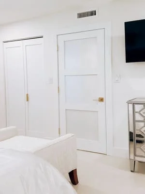 White bedroom with new six-panel doors, recessed lighting, and modern cabinetry