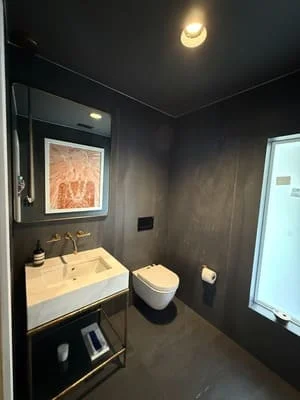 Dark tile bathroom with floating vanity, modern toilet, and accent lighting