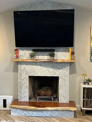 Marble herringbone fireplace surround with wood mantel and TV mount installation