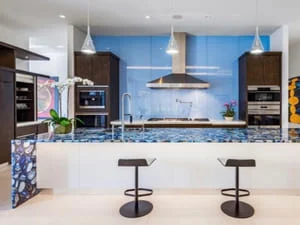 Modern kitchen with dark wood cabinets, white island, blue accent wall, stainless steel appliances