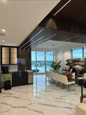 Modern residential interior with marble floors, wood ceiling slats, and floor-to-ceiling windows