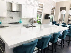 White kitchen with quartz island, stainless appliances, and subway tile backsplash