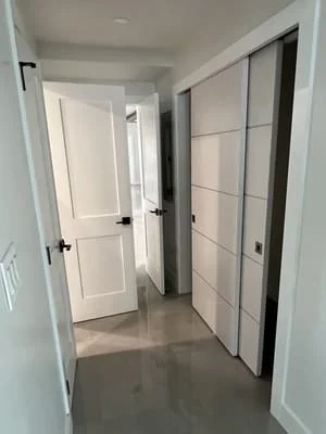 Modern hallway with polished concrete floor, white walls, and framed closet doors